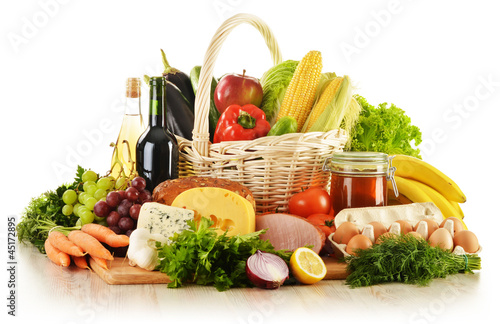 Photo: Groceries in wicker basket isolated on white Groceries in wicker basket isolated on white