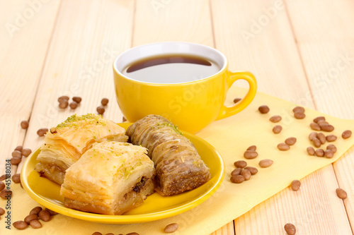 Photo: Sweet baklava on plate with tea on wooden background Sweet baklava on plate with tea on wooden background