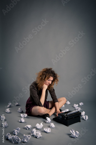 Photo: Young desperate girl writing with an old typewriter. Conceptual Young desperate girl writing with an old typewriter. Conceptual
