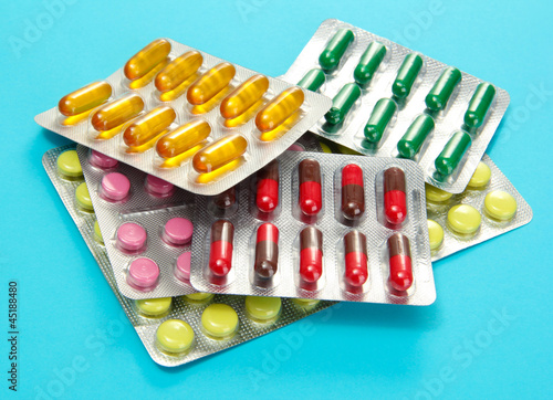 Photo: Capsules and pills packed in blisters, on blue background Capsules and pills packed in blisters, on blue background