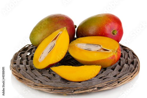 Photo: Ripe appetizing mango on wicker cradle isolated on white Ripe appetizing mango on wicker cradle isolated on white