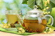 teapot and cup with linden tea and flowers
