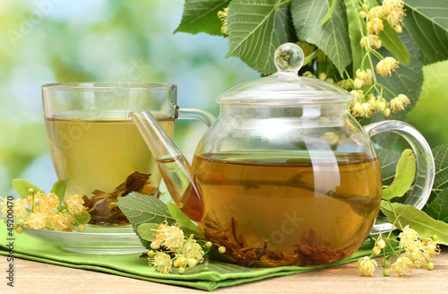 Photo: teapot and cup with linden tea and flowers teapot and cup with linden tea and flowers