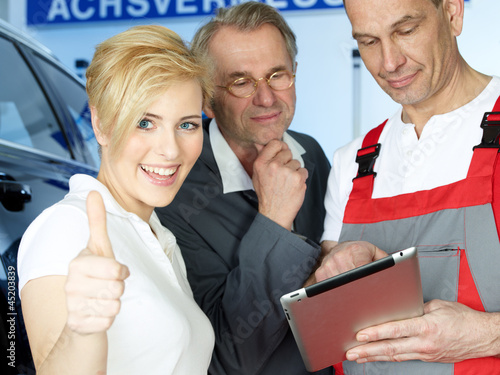 Photo: Female customer in garage shows thumb up for good service Female customer in garage shows thumb up for good service