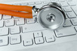 Helle Tastatur und orangefarbenes Stethoskop