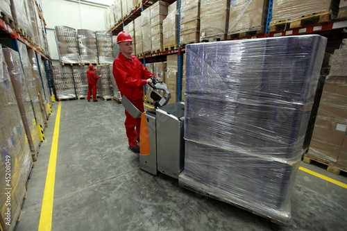 Photo: Two workers in uniforms working in storehouse Two workers in uniforms working in storehouse