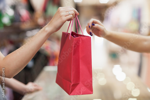 Photo: Woman handing over shopping bag Woman handing over shopping bag