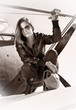 Beautiful girl in black jacket standing on a war aircraft.