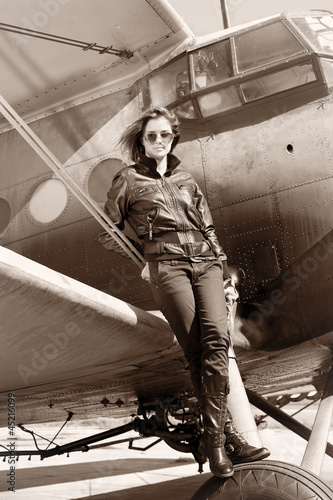 Photo: Beautiful girl in black jacket standing on a war aircraft. Beautiful girl in black jacket standing on a war aircraft.