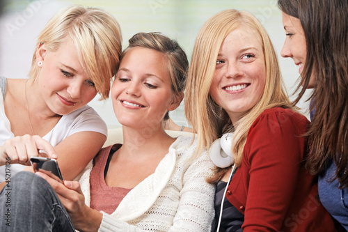 Photo: 4 girls with smartphones on the sofa 4 girls with smartphones on the sofa