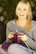 Hübsche blonde Frau beim Stricken auf der Terrasse