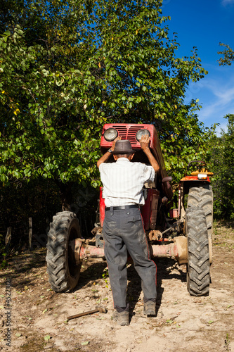 Photo: Senior farmer repairing his tractor Senior farmer repairing his tractor