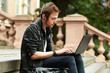 Happy student with laptop sitting on a stairs
