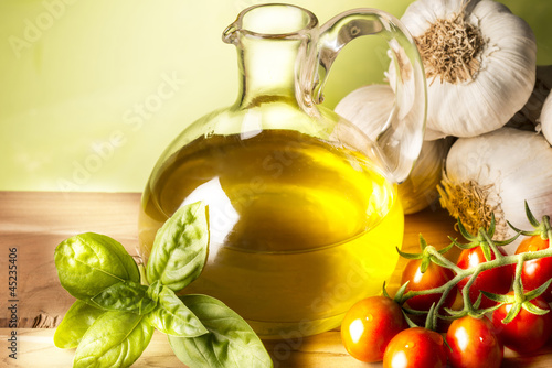 Photo: still life with olive oil,vegetables on wood table still life with olive oil,vegetables on wood table