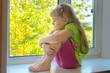 Foto: Cheerful girl looking at the beautiful trees outside the window. Cheerful girl looking at the beautiful trees outside the window.