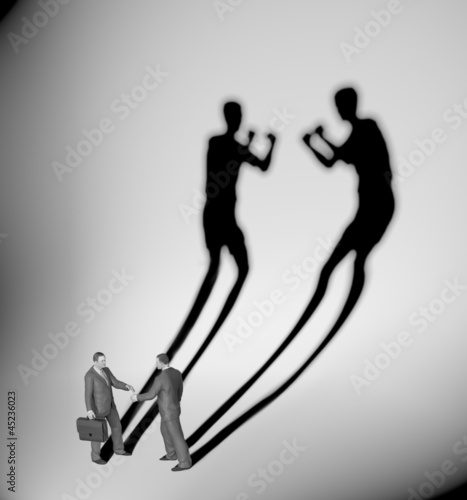 Illustration: Two businessman casting a shadow shaped like two fighters Two businessman casting a shadow shaped like two fighters