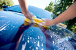 2 hands hold sponge over the car for washing