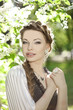 Photo: Woman with a hair braid in a blossoming park. Woman with a hair braid in a blossoming park.
