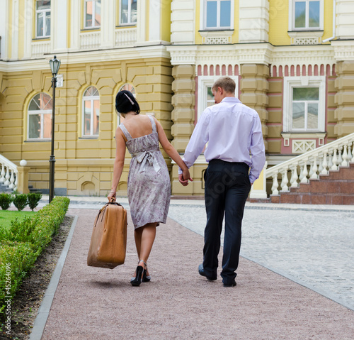 Photo: Couple walking with woman carrying luggage Couple walking with woman carrying luggage