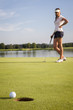 Girl golf player putting on green.