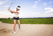 Woman golf player in sand trap preparing to hit the ball.