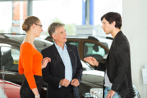 Photo: Älterer Mann mit Autos und jungem Pärchen im Autohaus Älterer Mann mit Autos und jungem Pärchen im Autohaus