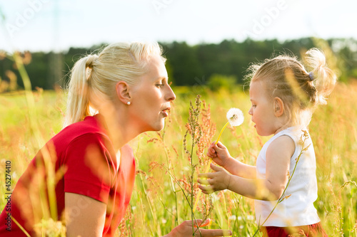 Photo: Mutter mit Tochter in der Wiese und pustet Löwenzahn Mutter mit Tochter in der Wiese und pustet Löwenzahn