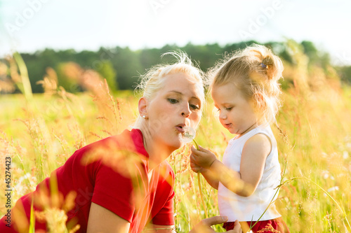 Photo: Mutter mit Tochter in der Wiese und pustet Löwenzahn Mutter mit Tochter in der Wiese und pustet Löwenzahn