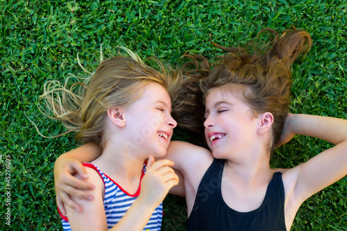 Photo: sisters kid girls smiling lying on garden grass sisters kid girls smiling lying on garden grass
