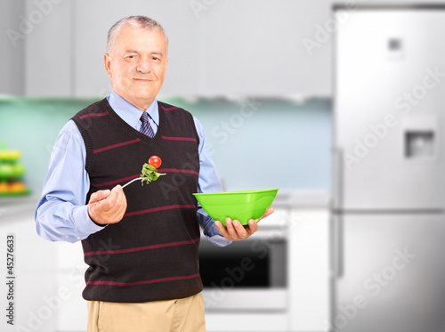 Photo: A mature man eating salad during a lunch A mature man eating salad during a lunch
