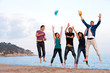 Group of young friends jumping on beach.