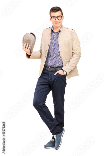 Photo: Full length portrait of a young man holding a hat Full length portrait of a young man holding a hat