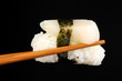 holding sushi with chopsticks isolated on black