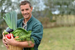 Photo: Portrait of smiling farmer holding vegetables basket Portrait of smiling farmer holding vegetables basket