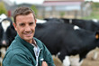 Photo: Herdsman standing in front of cattle in farm Herdsman standing in front of cattle in farm