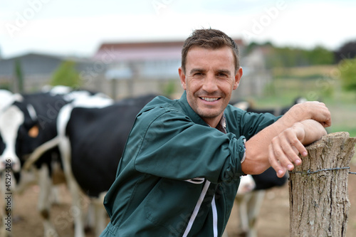 Photo: Herdsman standing in front of cattle in farm Herdsman standing in front of cattle in farm