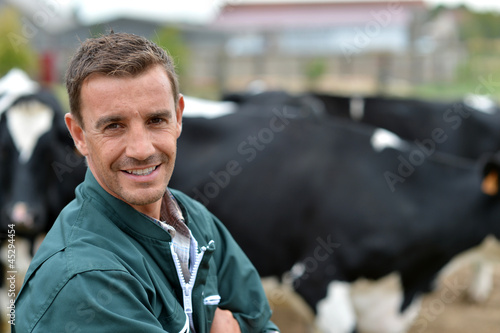 Photo: Herdsman standing in front of cattle in farm Herdsman standing in front of cattle in farm