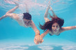 Photo: Underwater couple holding hands in swimming pool. Underwater couple holding hands in swimming pool.