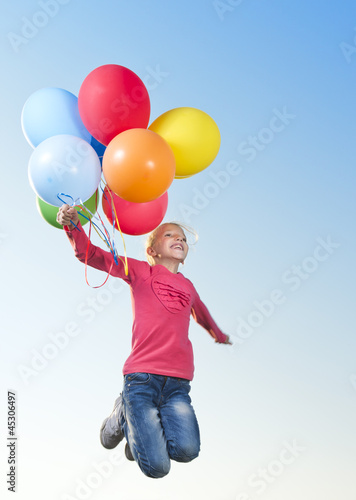 Photo: Girl jumping outside with balloons Girl jumping outside with balloons