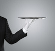 Waiter holding empty silver tray over gray background
