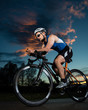 Photo: Triathlet auf dem Fahrrad bei Sonnenuntergang Triathlet auf dem Fahrrad bei Sonnenuntergang