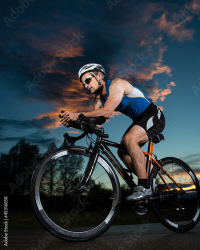 Photo: Triathlet auf dem Fahrrad bei Sonnenuntergang Triathlet auf dem Fahrrad bei Sonnenuntergang