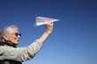 Photo: Senior woman playing with paper plane Senior woman playing with paper plane