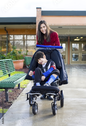 Photo: Teenage girl pushing little disabled boy in wheelchair Teenage girl pushing little disabled boy in wheelchair