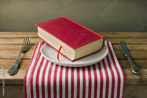 Photo: Book on plate with knife and fork. Table arrangement. Book on plate with knife and fork. Table arrangement.
