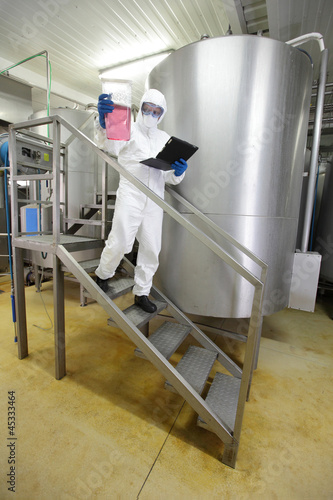 Photo: scientist with tablet checking sample in industrial interior scientist with tablet checking sample in industrial interior