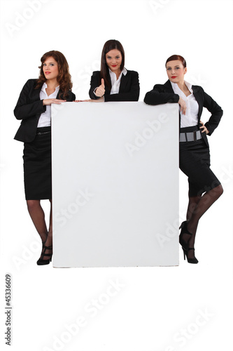 Photo: Business women stood with blank message board Business women stood with blank message board
