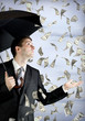 Business man holding an umbrella, money falling from the sky