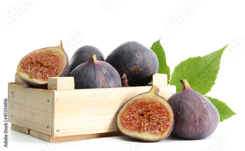 Photo: Ripe sweet figs with leaves in wooden crate isolated on white Ripe sweet figs with leaves in wooden crate isolated on white