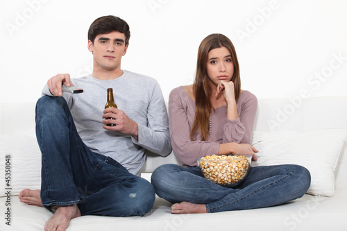 Photo: Bored man and woman watching TV Bored man and woman watching TV
